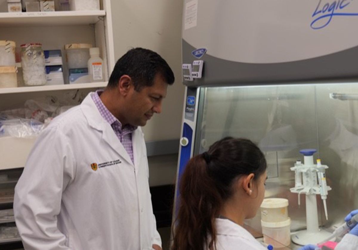 Pinaki Bose watches his student work in a biosafety cabinet.
