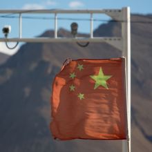 Chinese flag with surveillance cameras and mountains in background
