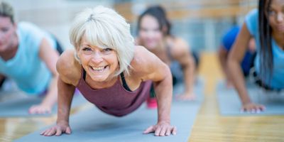 Woman smiling at the camera, working out on a blue yoga mat.